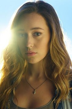 a woman with long hair is looking at the camera and has sun shining on her face