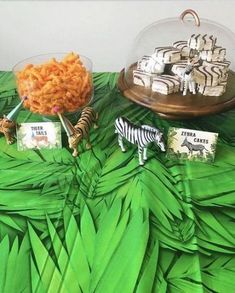 a table topped with lots of food and desserts on top of green leafy paper