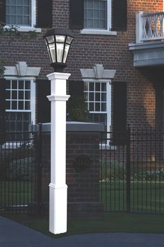 a white lamp post in front of a brick building