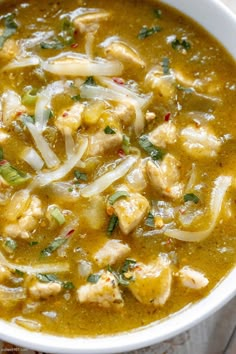 a white bowl filled with chicken and rice soup on top of a wooden cutting board