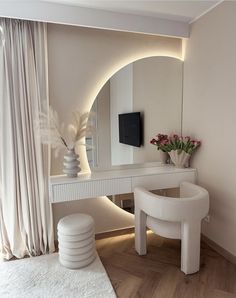 a white dressing table with mirror and stool in front of a large vase filled with flowers