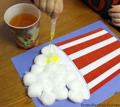 a child is painting an american flag with white cotton balls on a blue piece of paper