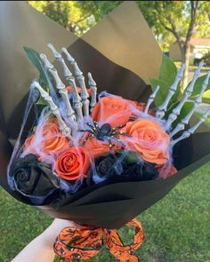 someone is holding a bouquet with roses and skeleton bones on it in the grass outside