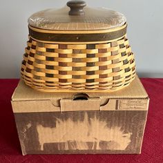 an old fashioned basket sitting on top of a cardboard box with the lid open and it's handle missing