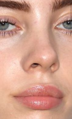 a woman with blue eyes and brown hair is looking at the camera while she has her nose pierced