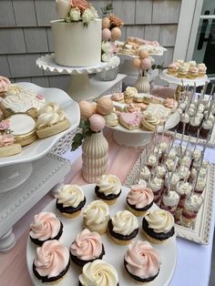 a table topped with lots of cupcakes next to cakes and desserts on plates