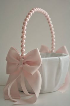 a white basket with a pink bow and pearls on the handle is sitting on a table