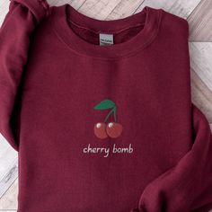 Cherry Bomb Sweatshirt, Cute Cherries Sweater, Embroidered Cherry Shirt, Embroidered Fruit Sweater, Cute Crewneck Sweater, Cute Cherry Shirt This embroidered cherry bomb crewneck sweatshirt is everything.  Please let me know if you would like extended sizing (3X-5X), I have certain color and size options available! ✨ 50% cotton, 50% polyester ✨ Pre-shrunk ✨ Classic fit Care: Machine wash: warm (max 40C or 105F) Tumble dry: low Do not iron directly on the print About me: My name is Sarah and I am Cherry Clothes, Fruit Sweater, Cherry Hoodie, Embroidered Fruit, Cherry Sweater, Cherry Shirt, Cute Crewneck, Sweater Cute, Sweatshirt Cute