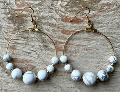 "-These lightweight hoop earrings are made with white howlite beads -Earrings measure approx 2 5/8\" drop with hook, 1 7/8\" wide -Gold plated brass ear hooks -Made in New York Each piece is unique. Pairs are very closely matched, but some variations are to be expected and your earrings may not be identical to the earrings pictured. The color, shade, texture or pattern may vary slightly from what is shown depending on your monitor or screen on which you are shopping. Each pair of earrings come o Adjustable White Wire Wrapped Hoop Earrings, White Wire Wrapped Dangle Hoop Earrings, Adjustable White Hoop Earrings With Ear Wire, Adjustable Nickel-free White Hoop Earrings, Adjustable White Nickel Free Hoop Earrings, Adjustable Hoop Earrings With Natural Stones, White Wire Wrapped Round Bead Earrings, White Wire Wrapped Small Hoop Earrings, White Wire Wrapped Small Hoop Jewelry