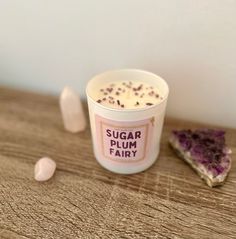 a cup of sugar plum fairy next to a slice of cake on a wooden table