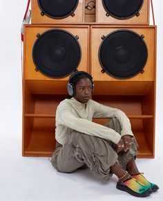 a person sitting on the ground with headphones in front of a boombox and speakers