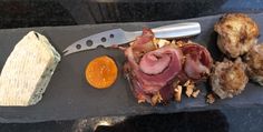 an assortment of meats and cheese on a slate platter with a chef's knife