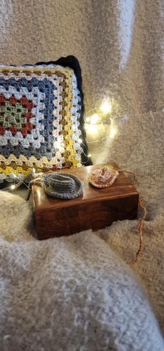 a crocheted pillow sitting on top of a bed next to a wooden box