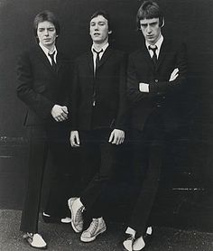 three young men in suits and ties posing for a black and white photo with their arms crossed