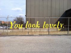 a sign that says you look lovely on the side of a fenced in parking lot