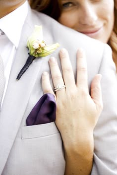 a woman in a white suit and purple tie with a flower on her lapel