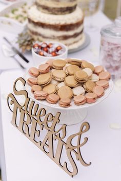 a table topped with lots of cakes and desserts next to a sign that says sweet treats