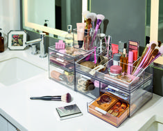 a bathroom counter with makeup and other items on top of it next to a mirror