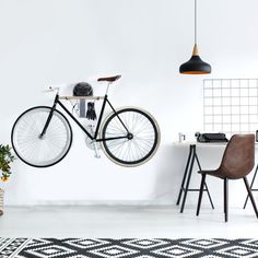 a black and white bicycle hanging from the wall next to a table with two chairs