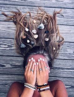 a woman with her hands on her face and seashells all over her hair