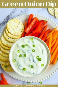 green onion dip with carrots and crackers on a plate