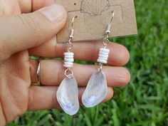 a pair of earrings with white glass tears hanging from it's ear wires