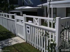 a white picket fence in front of a house with a mailbox on the gate