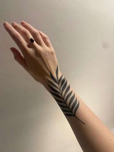 a woman's arm with a black and white tattoo design on the left wrist