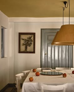 a dining room table with white chairs and an apple centerpiece on top of it