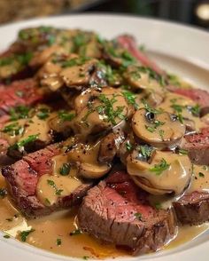 steak with mushrooms and gravy on a white plate