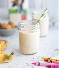 a glass jar filled with smoothie next to bananas and other food on the table