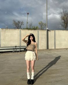 a woman standing in an empty parking lot with her hands on her head and wearing short white socks