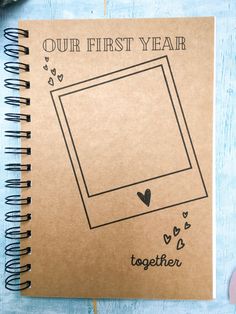 a spiral notebook with the words, our first year together on it next to a cup of coffee