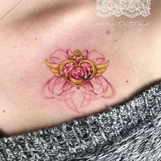 a woman's chest with a heart and wings tattoo on her chest, surrounded by pink flowers