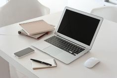 an open laptop computer sitting on top of a desk next to a mouse and notebook