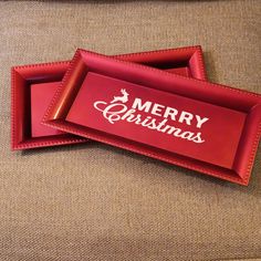 two red trays sitting on top of a couch with merry christmas written on them