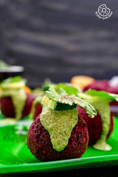 strawberries covered in avocado on a green plate with other fruits and vegetables