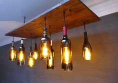 several wine bottles are hanging from the ceiling with light bulbs in between them and on top of each other