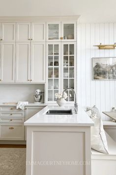 a kitchen with white cabinets and an island in the middle, along with gold accents