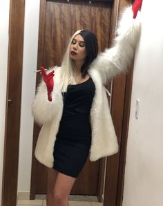 a woman in a short black dress and white fur coat posing for the camera with her arms outstretched