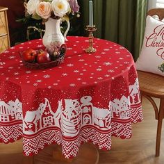 a red table cloth with white designs on it and a vase filled with flowers in the center