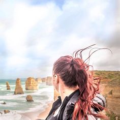 a woman looking out at the ocean and cliffs