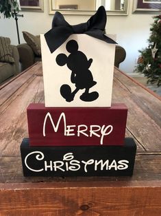 a wooden block with a mickey mouse on it and a merry christmas sign next to it