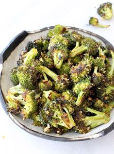 a plate full of cooked broccoli on a table