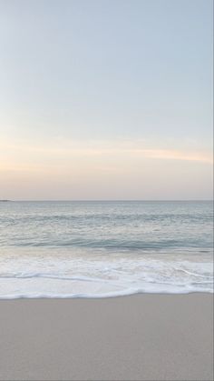 an empty beach with the ocean in the background