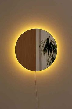 a round mirror sitting on top of a wall next to a potted palm tree