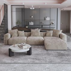 a living room with a large sectional couch and coffee table in front of the stairs