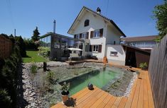 a house with a pool in the middle of it's yard and wooden decking