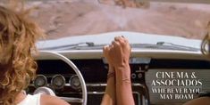 two women are driving in a convertible car on the desert road, one is holding her hand up to the driver's wheel