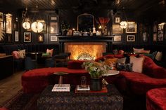 a living room filled with lots of red couches and chairs next to a fire place